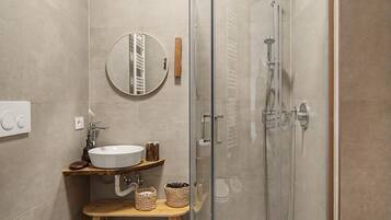 Une salle de bain moderne avec une douche à parois de verre, un miroir rond et un meuble-lavabo en bois.