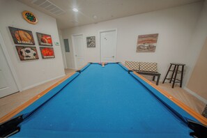A pool table with a blue felt surface, surrounded by walls with sports-themed decorations. - Go!#13 WINDSOR AT WESTSIDE (Kissimmee)