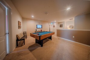 Ein Zimmer mit Billardtisch, Fernseher und Dartscheibe.