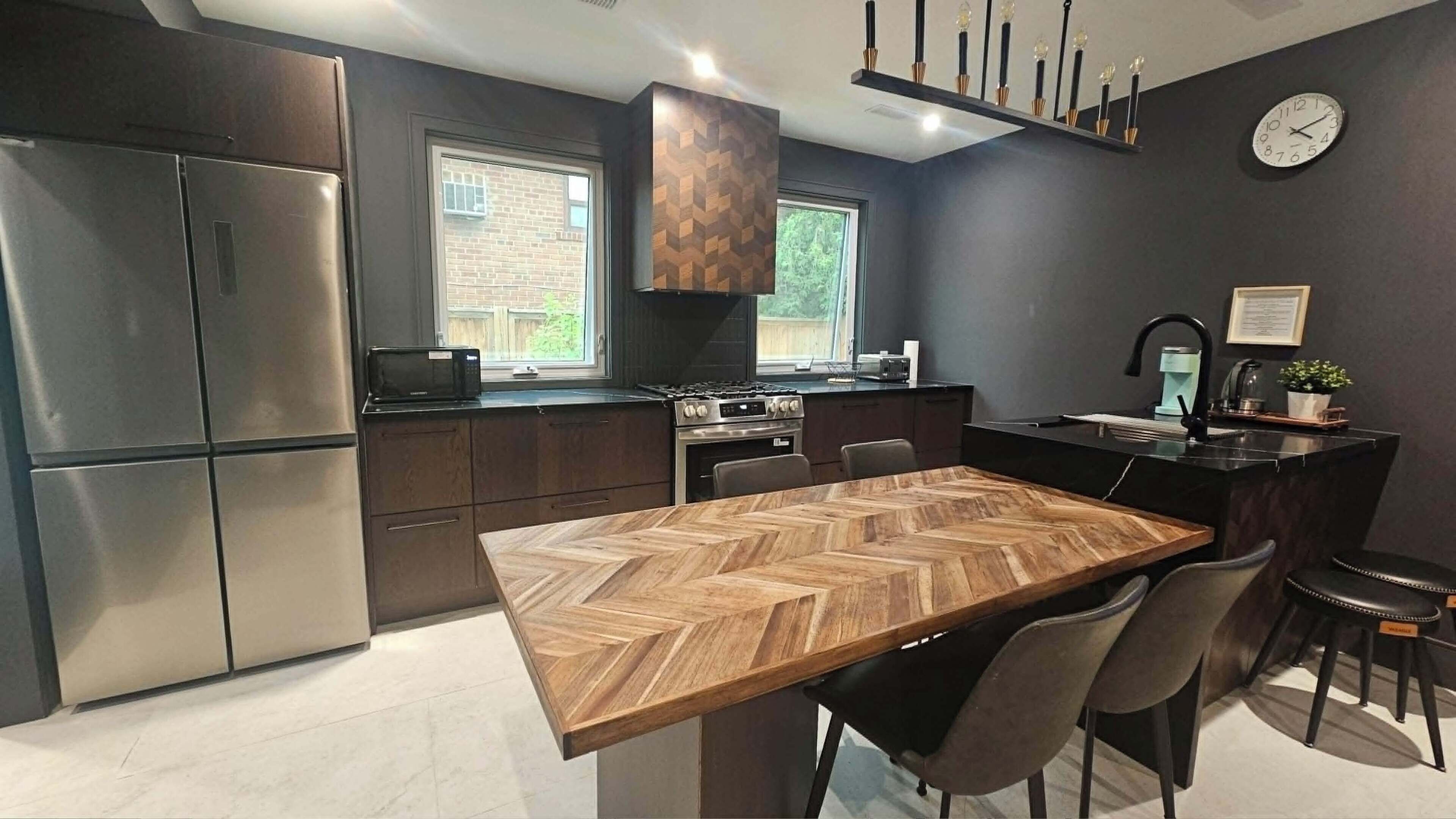 A modern kitchen with a central island, stainless steel appliances, and a dining area with a herringbone wood table.