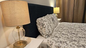 Ein Hotelzimmer mit einem Bett, einem Nachttisch, einer Lampe und einem Vorhang.
