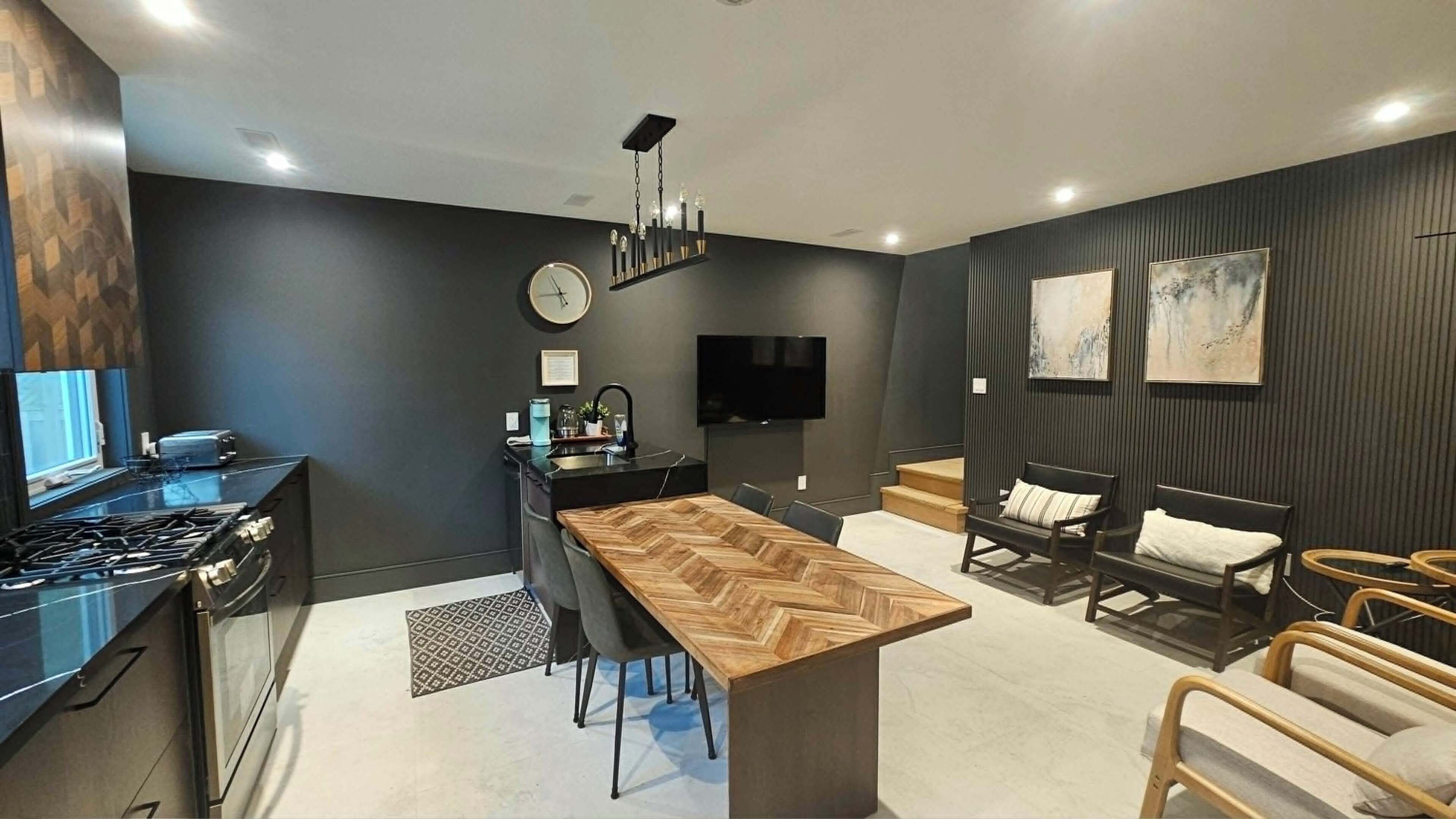 A modern kitchen with a central island, a dining area with a long table, and a seating area with chairs and sofas.