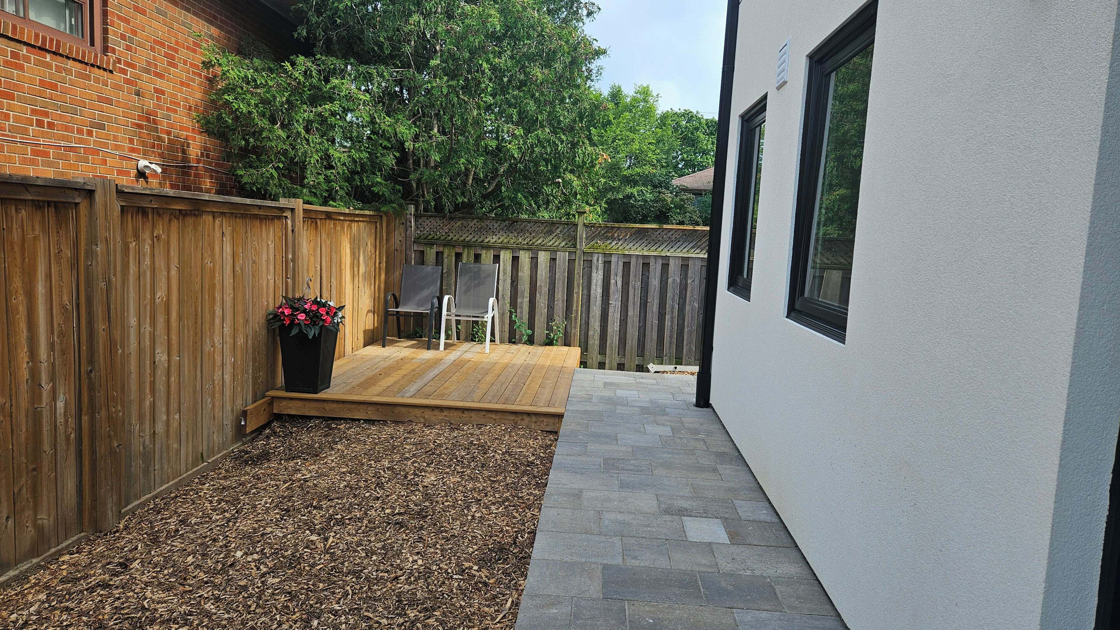A patio area with a wooden deck, a seating area with chairs, and a potted plant.