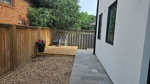 Eine Terrasse mit Holzdeck, einer Sitzecke mit Stühlen und einem Blumentopf.