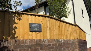 A brick wall with a wooden fence and a sign indicating 'BLORENGE VIEW HOUSE 24 LANNOVER WAY'.