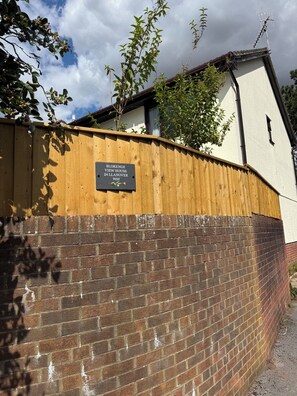 A brick wall with a wooden fence and a sign indicating 'BLORENGE VIEW HOUSE 24 LANNOVER WAY'.