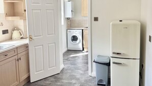 A compact kitchen with a washing machine, a refrigerator, and a sink.