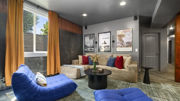 Ein modernes Wohnzimmer mit einer Sofagarnitur, einem blauen Sitzsack, einem Couchtisch und einer Tür zu einem weiteren Raum.