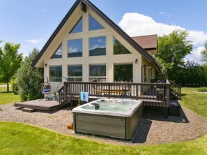 A two-story house with a deck, hot tub, and outdoor seating area.