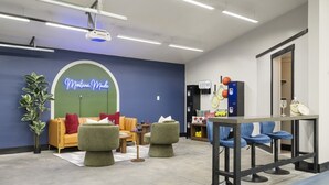 Eine Lounge mit Sitzgelegenheiten, einer Neonreklame, Schließfächern und Sportausrüstung.