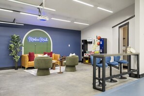 Eine Lounge mit Sitzgelegenheiten, einer Neonreklame, Schließfächern und Sportausrüstung.