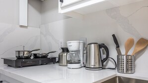 Eine moderne Küche mit Gasherd, Kaffeemaschine, Wasserkocher und Kochgeschirr.
