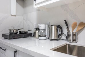 Eine moderne Küche mit Gasherd, Kaffeemaschine, Wasserkocher und Kochgeschirr.