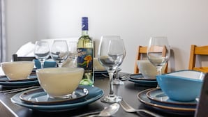 A dining table set with blue and white plates, bowls, and wine glasses, along with a bottle of wine. - Serenity by the Falls: Modern 2 Bedroom Hideaway (Niagara Falls)