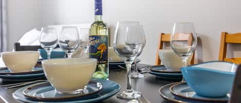 A dining table set with blue and white plates, bowls, and wine glasses, along with a bottle of wine.