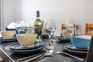A dining table set with blue and white plates, bowls, and wine glasses, along with a bottle of wine. - Serenity by the Falls: Modern 2 Bedroom Hideaway (Niagara Falls)