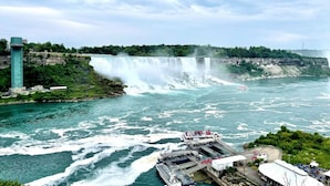 A large waterfall with a viewing platform and a tall tower. - Serenity by the Falls: Modern 2 Bedroom Hideaway (Niagara Falls)