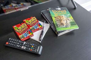 Ein Tisch mit einem Buch mit dem Titel 'Leopard Rescue', einer Fernbedienung und einer 'UNO EXPRESS'-Spielebox.