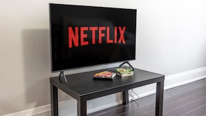 A television mounted on a wall with the word "NETFLIX" displayed on the screen. - Serenity by the Falls: Modern 2 Bedroom Hideaway (Niagara Falls)