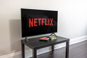 A television mounted on a wall with the word "NETFLIX" displayed on the screen. - Serenity by the Falls: Modern 2 Bedroom Hideaway (Niagara Falls)
