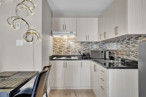 Una cocina moderna con armarios de madera clara, encimera negra y salpicadero decorado.