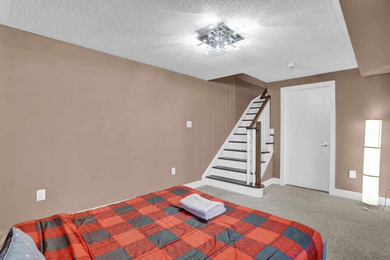 Een slaapkamer met een bed, een trap en een deur.