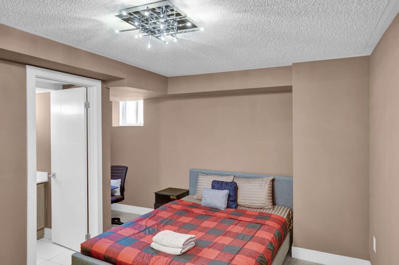 Une chambre à coucher comprenant un lit, une table de chevet, une chaise et une porte donnant sur une autre pièce.