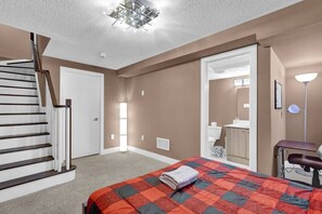 Une chambre à coucher comprenant un lit, un bureau, une chaise, une salle de bain et un escalier.