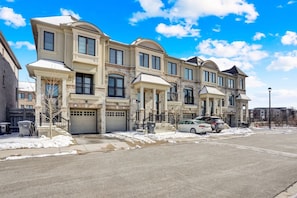 A row of townhouses with a garage, a driveway, and a street.