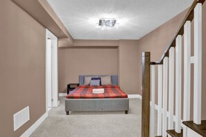 Un dormitorio con cama, mesita de noche y una escalera.
