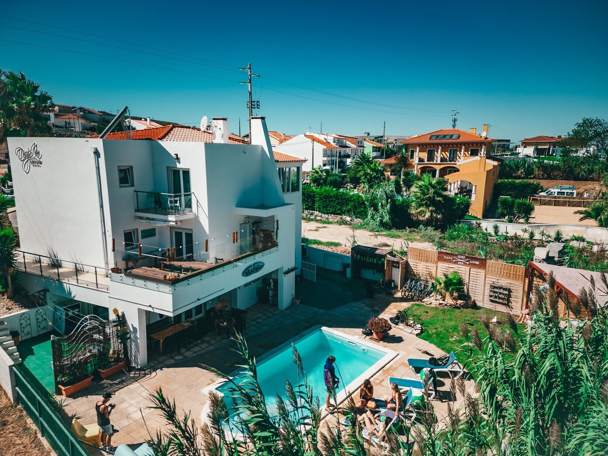 Un moderno edificio de dos pisos con piscina, asientos exteriores y vista al mar.