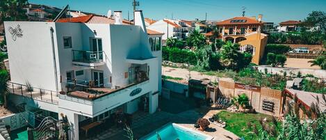 Un moderno edificio de dos pisos con piscina, asientos exteriores y vista al mar.