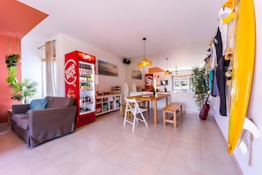 Ein zeitgemäßer Wohnraum mit Sofa, Esstisch mit Stühlen, Küchenzeile und einem Surfbrett.