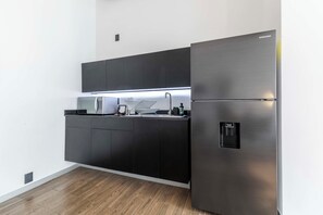 A modern kitchen with a stainless steel refrigerator, a microwave, and a sink. - JA 303 Minimalist Comfort Near Bellas Artes (Centro)