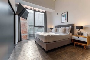 A modern bedroom with a large bed, bedside lamps, a nightstand, and a framed picture on the wall. - JA 303 Minimalist Comfort Near Bellas Artes (Centro)