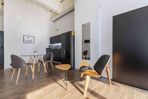 A modern kitchen with a black refrigerator, a dining table with chairs, and a large black door. - JA 303 Minimalist Comfort Near Bellas Artes (Centro)