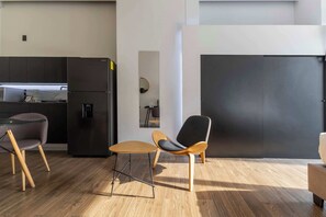 A modern kitchen with a black refrigerator, a dining table with two chairs, and a large black door. - JA 303 Minimalist Comfort Near Bellas Artes (Centro)