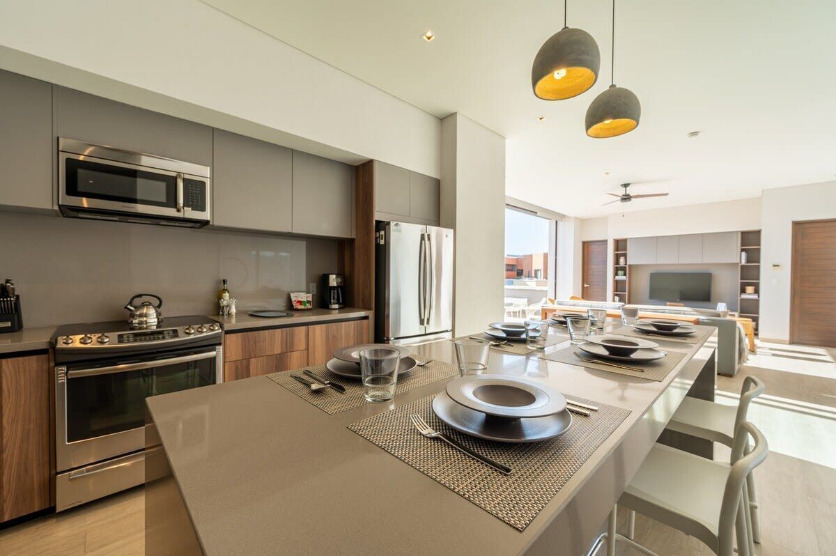 A modern kitchen with a central island, stainless steel appliances, and pendant lighting.