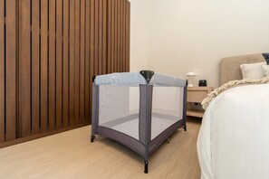 Ein Zimmer mit einem Bett, einer Wand aus Holzpaneelen und einem Reisebettchen.
