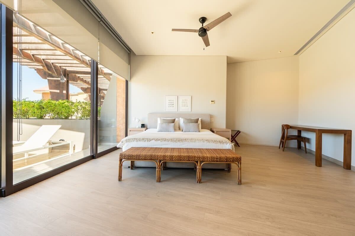 Une chambre à coucher avec un lit, un banc en bois, une table et un ventilateur de plafond.