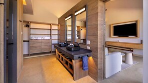 A modern bathroom with a wooden vanity, two sinks, a large mirror, and a television mounted on the wall. - Diamante Beach Estate 47 (Cabo San Lucas)