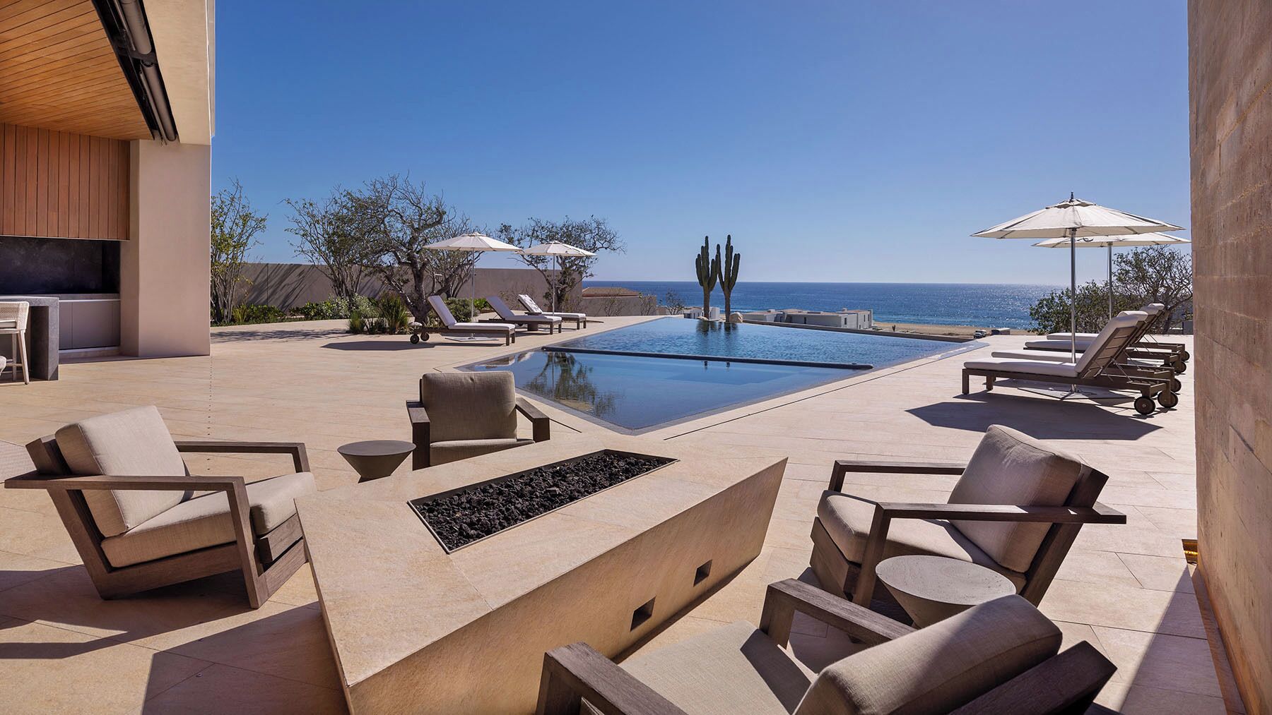 Ein Poolbereich mit Liegestühlen, einer Feuerstelle und Blick aufs Meer.