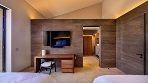 A modern bedroom with a wooden wall, a desk with a chair, a bed, and a walk-in closet. - Diamante Beach Estate 47 (Cabo San Lucas)