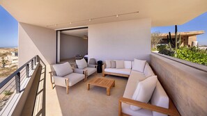 Ein Balkon mit einer Sitzecke, einem Couchtisch und einem Sessel.