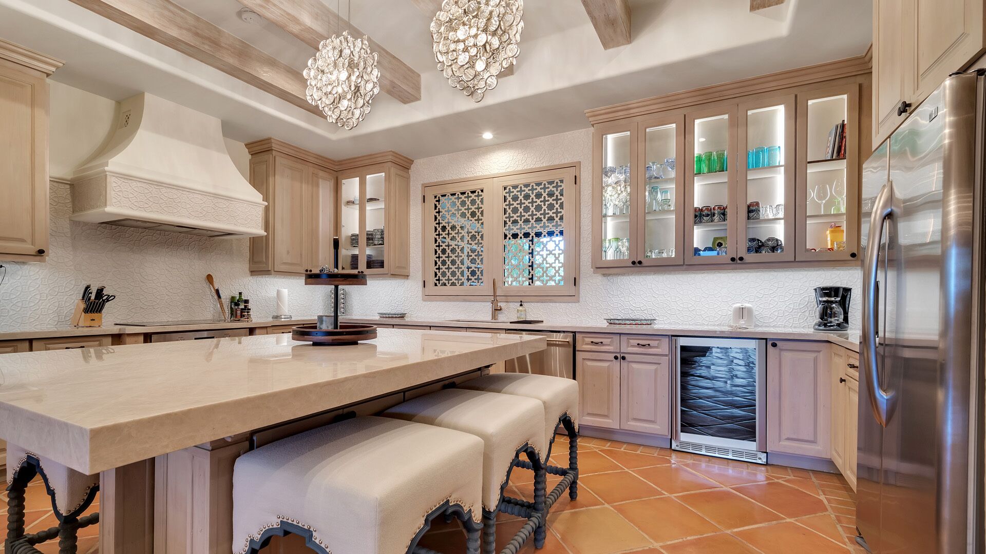 A modern kitchen with a central island, built-in appliances, and a decorative chandelier.