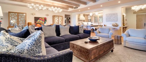 Amplia sala de estar con un sofá azul oscuro, cojines estampados y una mesa de centro de madera.