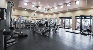 A gym with various exercise equipment, large windows, and ceiling fans. - Diamante Golf Villa 39 (Cabo San Lucas)