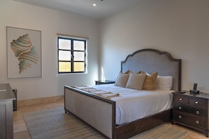 A bedroom with a bed, bedside tables, a nightstand, a window, and a wall-mounted artwork. - Diamante Golf Villa 39 (Cabo San Lucas)