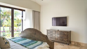 A bedroom with a bed, a TV mounted on the wall, and a window with curtains. - Diamante Golf Villa 39 (Cabo San Lucas)