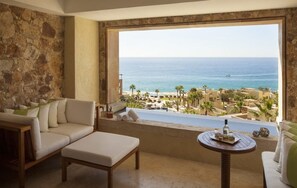 Ein Zimmer mit Steinwand, einer Couch, einem kleinen Tisch und Blick auf den Ozean sowie das Resort.